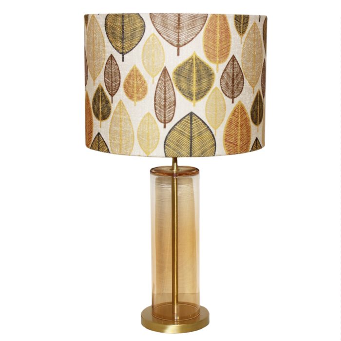 Table lamp with cylindrical base in golden transparent glass and cylindrical lamp shade with brown, cream, green leaves