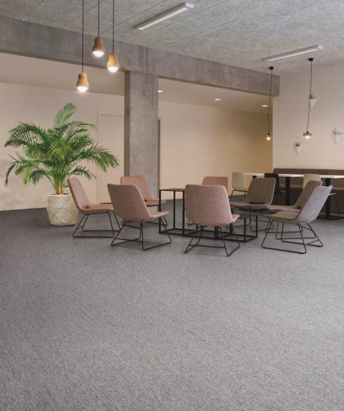 Commercial space with dark sisal carpet, dark pink chairs, table and a plant
