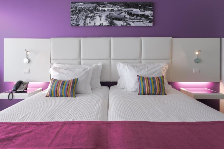 Quarto de hotel com duas camas, almofadas decorativas e cabeceira de cama