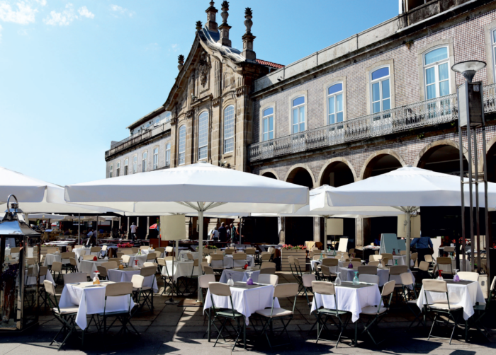 Esplanada exterior com mesas, cadeiras e guarda-sóis brancos