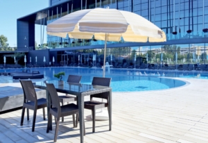 Exterior of a swimming pool, with a set of tables and chairs and a parasol